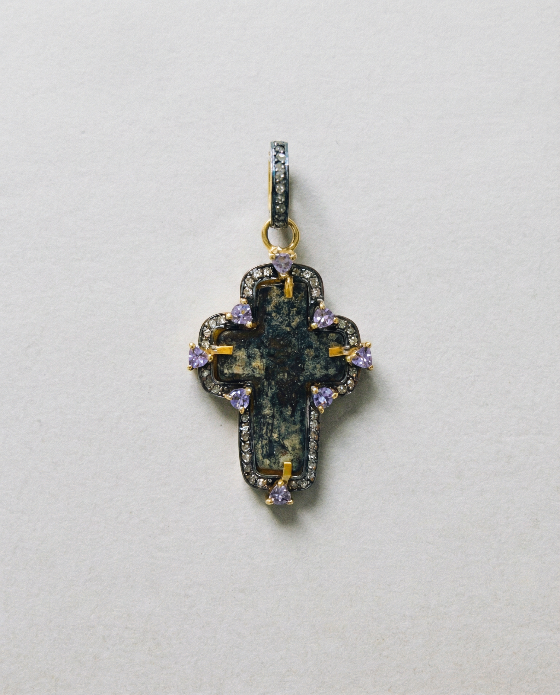 Close-up of authentic 17th–18th century sand-cast copper Old Believers Christian cross with historical patina and engravings, set in 24kt gold-plated sterling silver with diamond and tanzanite accents on a vintage paper. 
