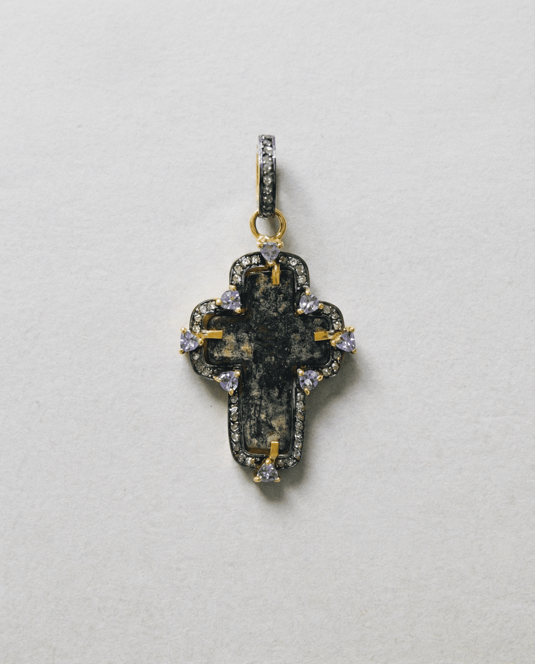 Close-up of authentic 17th–18th century sand-cast copper Old Believers Christian cross with historical patina and engravings, set in 24kt gold-plated sterling silver with diamond and tanzanite accents on a vintage paper. 