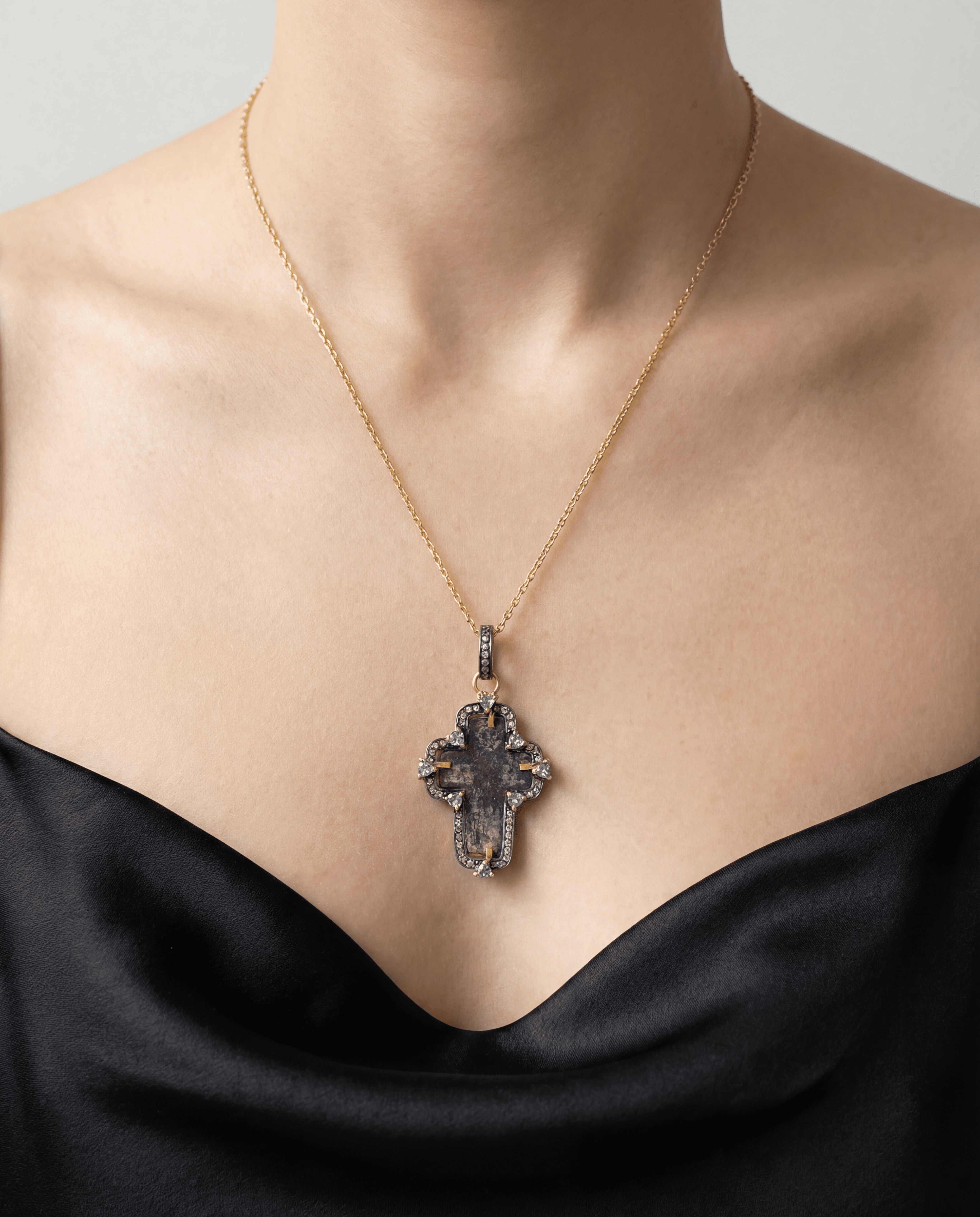 Antique 17th–18th century Russian Orthodox Old Believers cross in 24kt gold-plated silver frame with aged copper patina, 0.6ct natural diamonds and 1.04ct violet tanzanite worn by a model against a neutral background