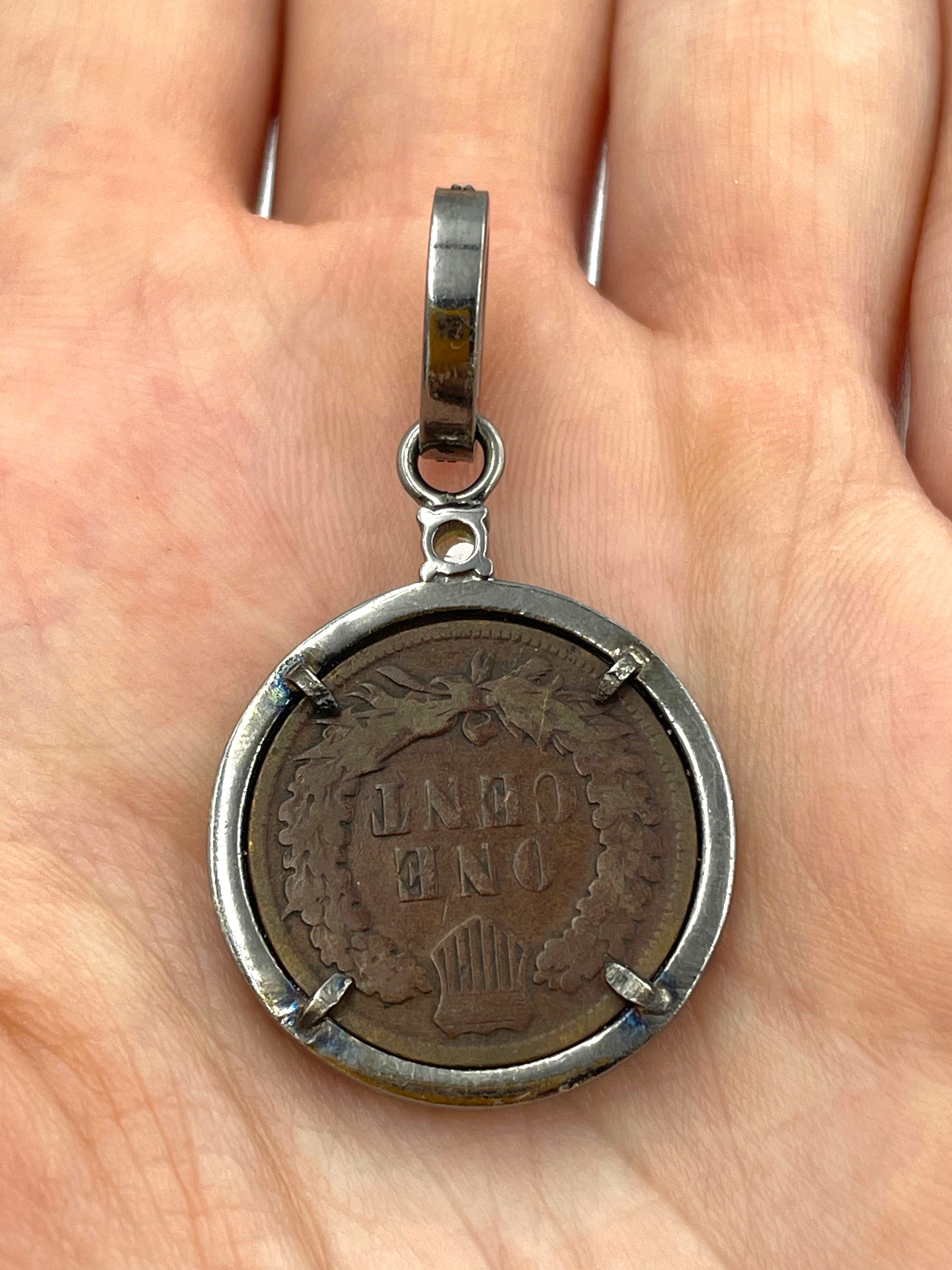Reverse of 1905 Indian Head Penny pendant showing oak wreath and shield, framed in sterling silver with 24 natural diamonds 0.36ct held in a hand