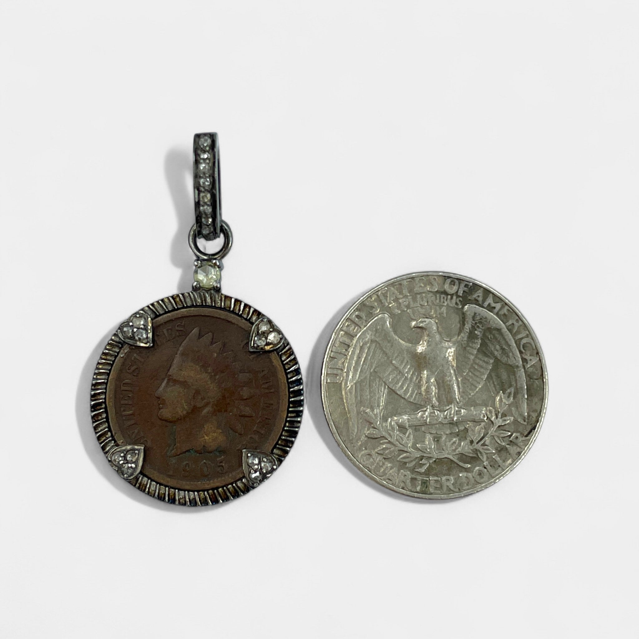 Two coins, one diamond-accented bail on 1905 Indian Head cent necklace in sterling silver with 0.36ct natural diamonds and original copper patina and another with an eagle emblem, on a white background.